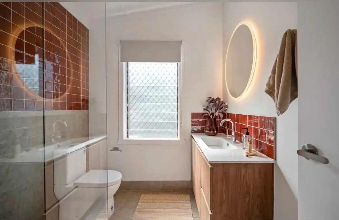 Bathroom project finished view, with an illuminated round mirror in the finished room